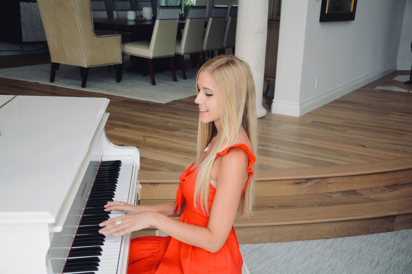 Joanna Holstein at a white grand piano in a red dress